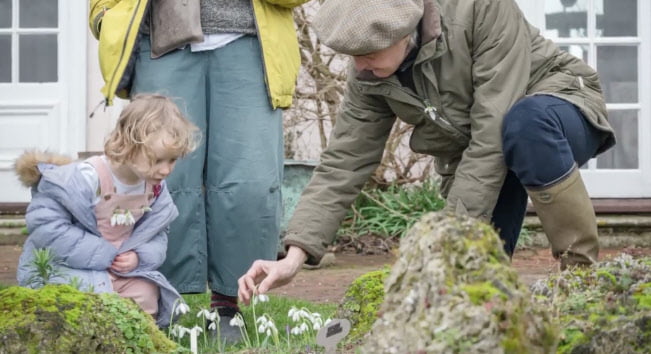 child and adult looking at snowdrops