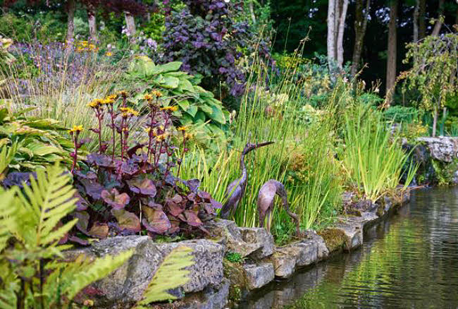sculpture of birds in garden by a lake