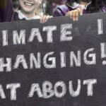 children holding sign saying climate is changing what about you
